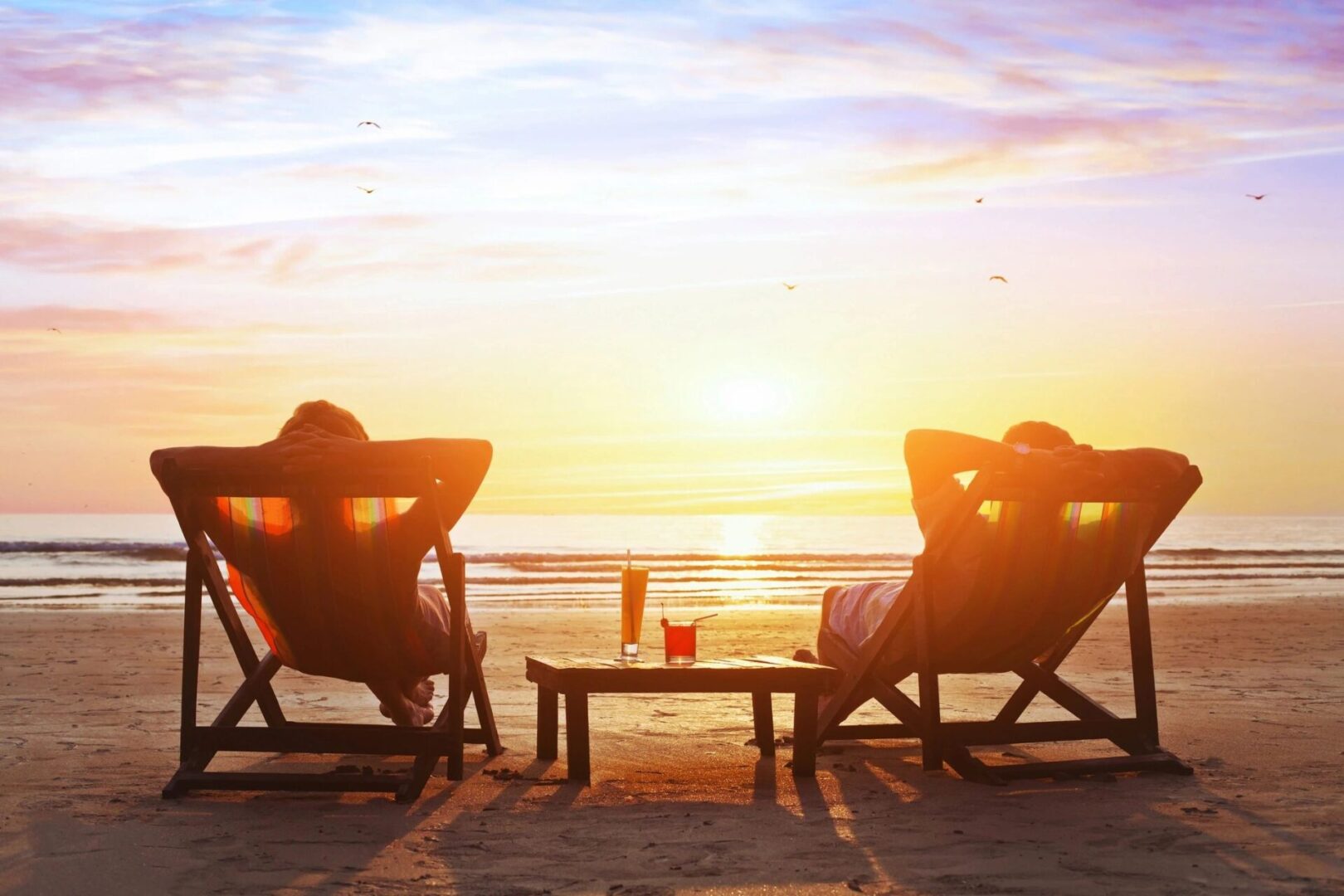 Two people sitting on lawn chairs at the beach