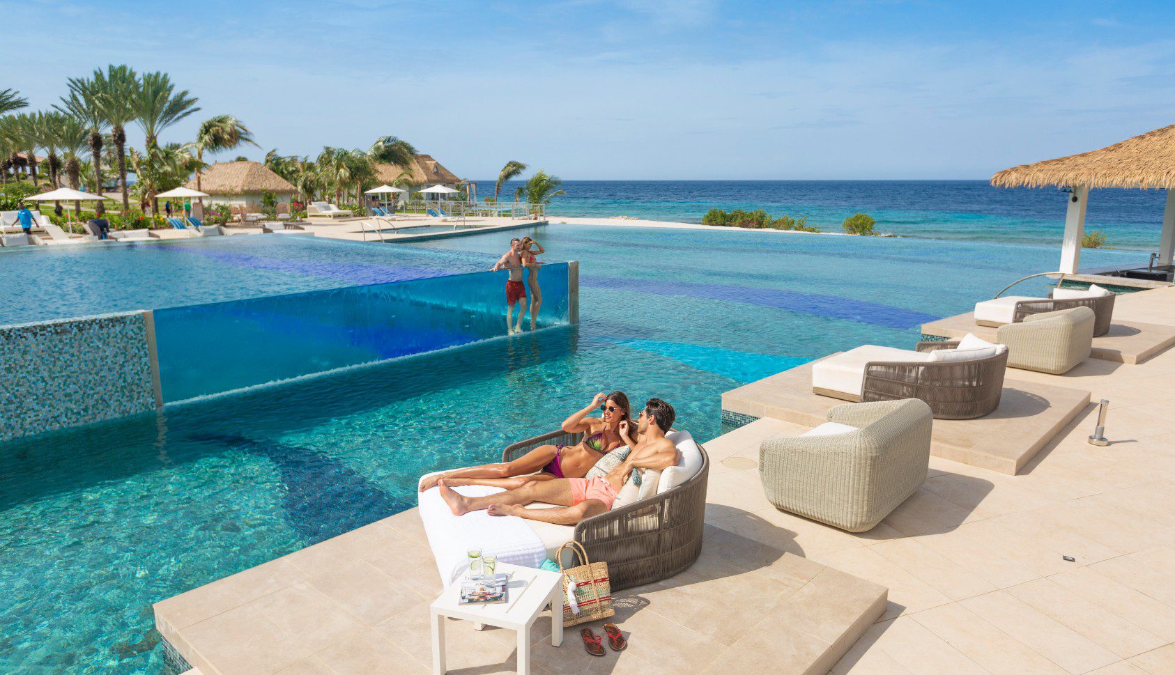 Two people sitting on a couch in front of the pool