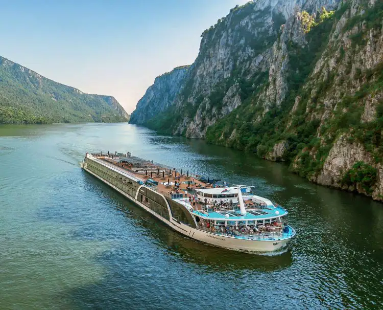 A large boat floating on top of water near mountains.