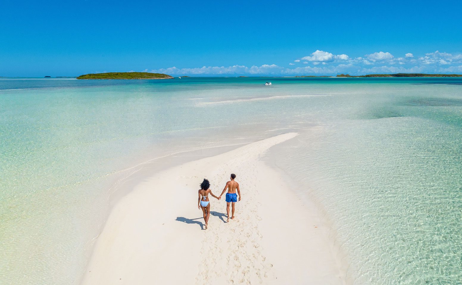 Two people walking on the beach holding hands